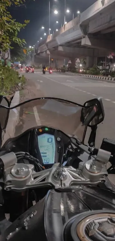 Motorcycle on city road at night under urban lights.