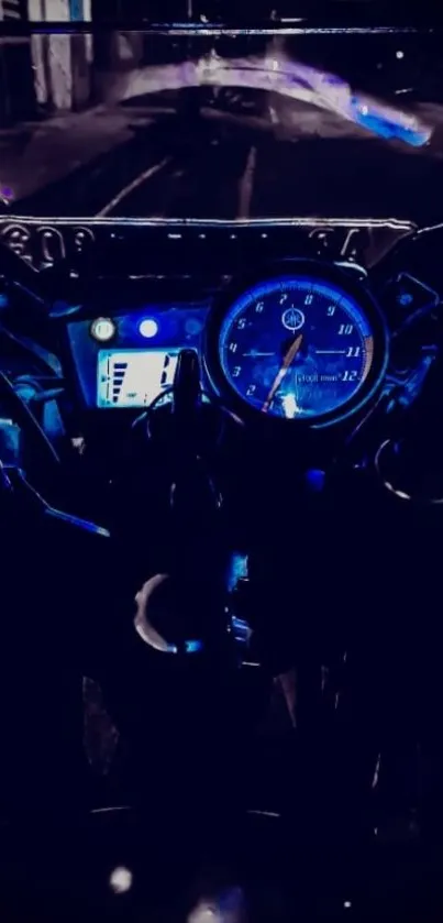 Motorcycle dashboard at night with blue lights on a dim street.