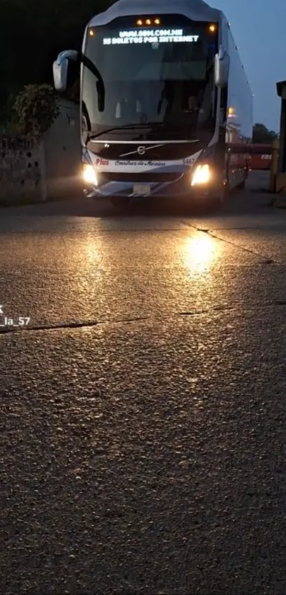 A bus traveling on a road at night, illuminated by streetlights.