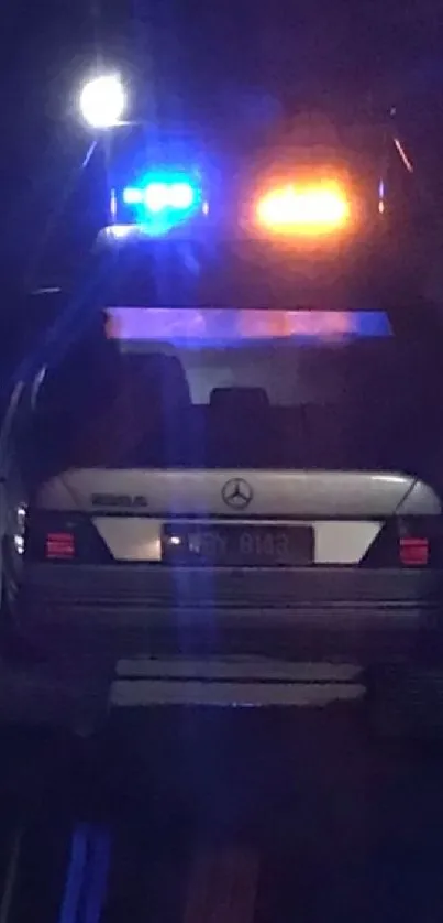 Nighttime roadside assistance with blue and orange lights illuminating a car.