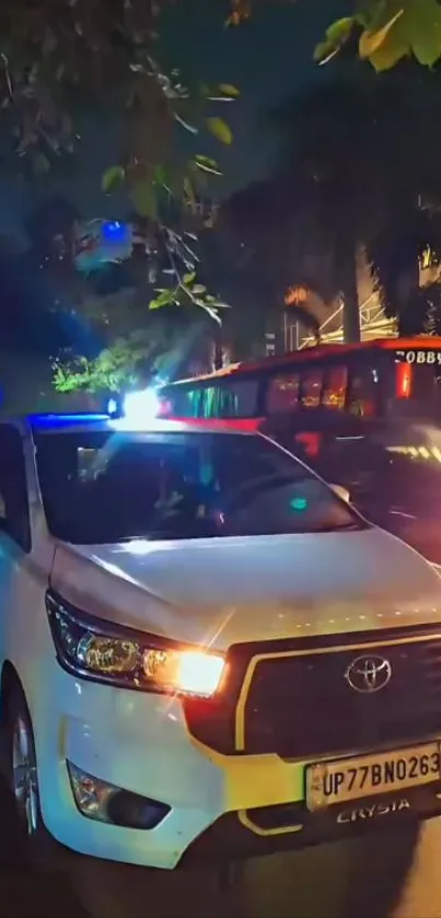 White car on a city street at night with vibrant lights.