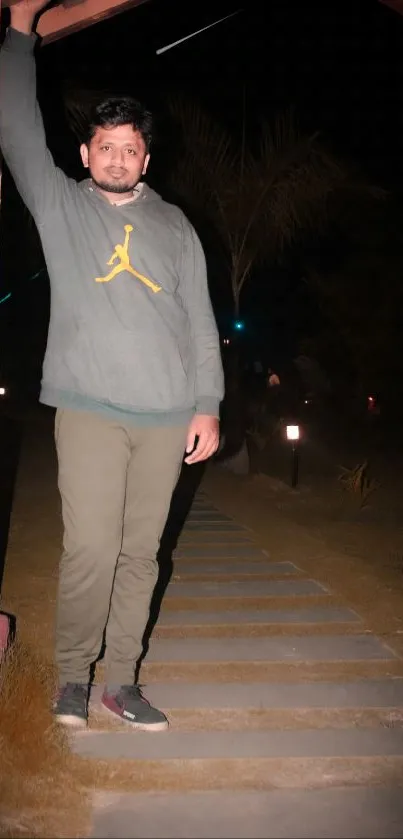 A man stands under a glowing archway on a peaceful night pathway.