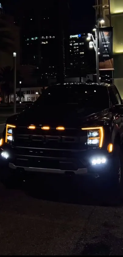 Black truck in city at night with illuminated headlights.