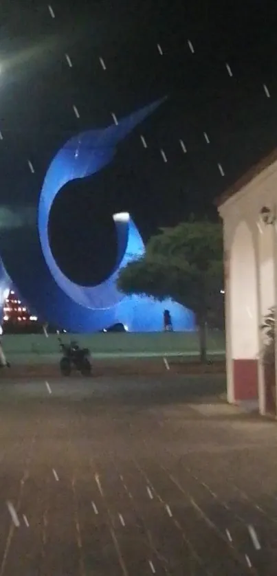 Night scene with blue wave sculpture under streetlights.