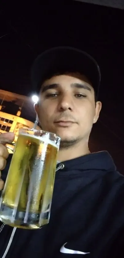 Young man with beer glass at night