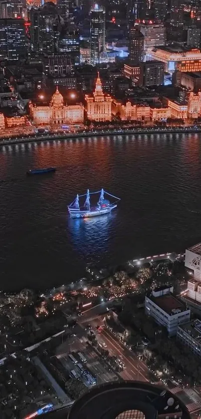 A nighttime city harbor with illuminated buildings and a ship on the river.