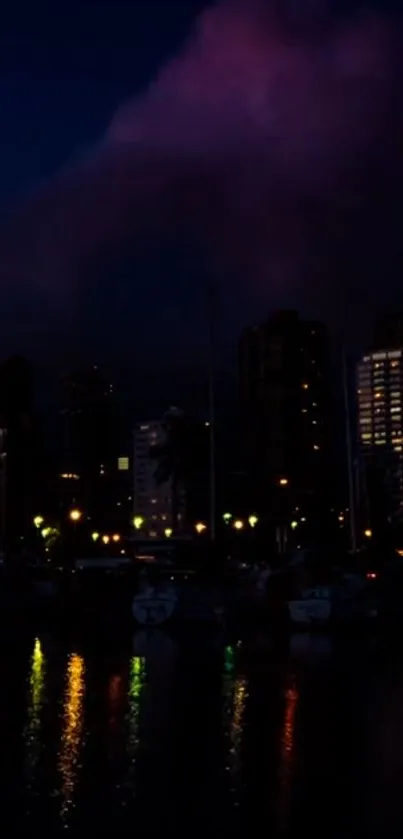 Dark cityscape at night with colorful reflections on water.