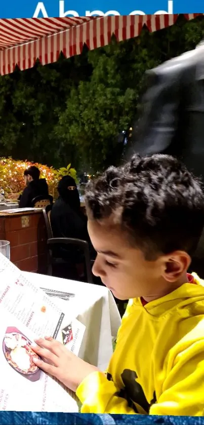 Young boy dining outdoors under night sky.