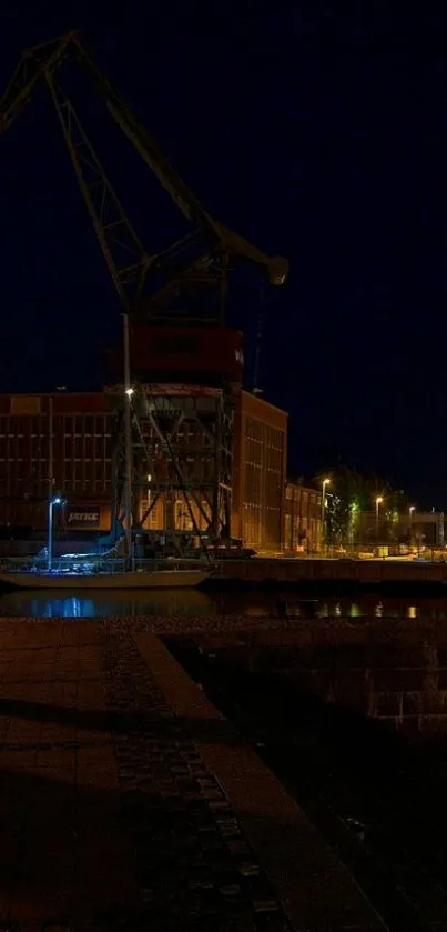 Nighttime harbor with crane silhouetted against a navy blue sky.