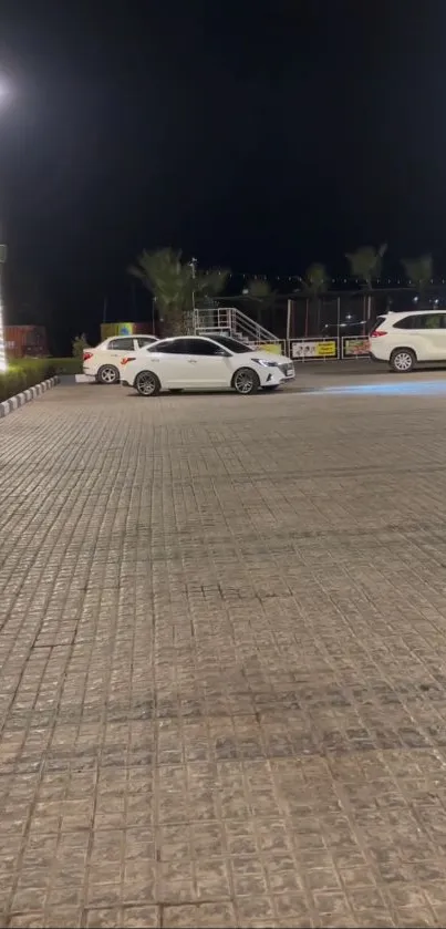 Calm night parking lot with cars under streetlights.