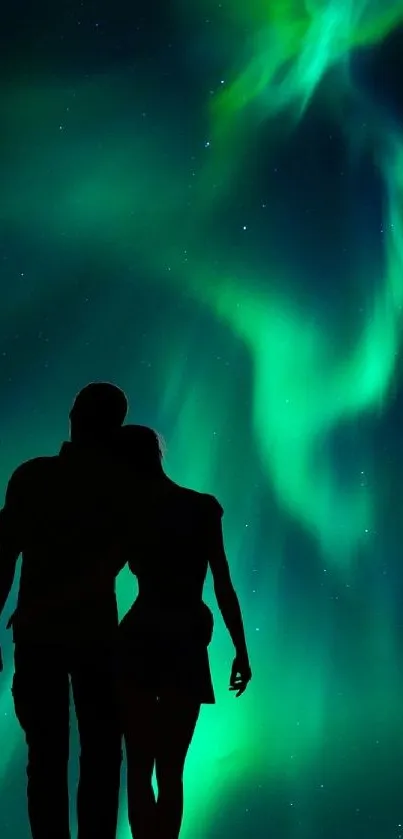 Silhouette couple under teal Northern Lights display.