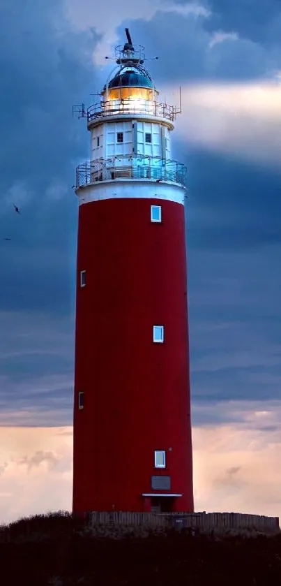 A tall red lighthouse against a dramatic blue sky.