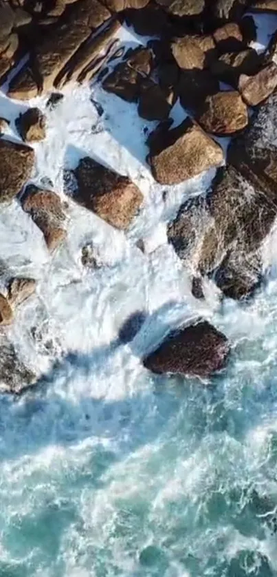 Aerial view of waves crashing on rugged coastal rocks.