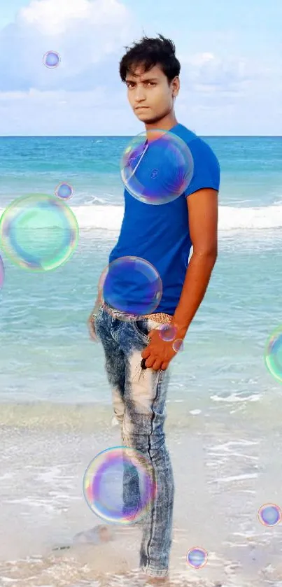 Young man in blue shirt on a beach with ocean and sky.