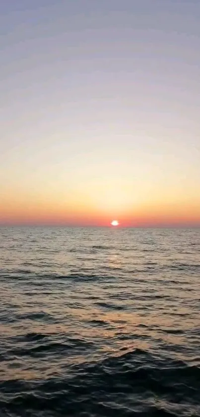 A beautiful ocean sunset with a glowing horizon and calm sea waves.