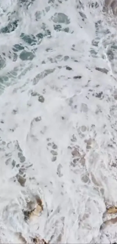 Aerial view of ocean waves with white foamy texture on rocks.