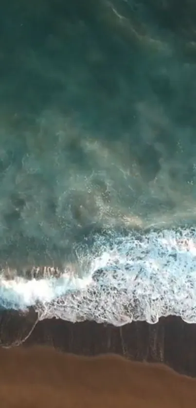 Aerial view of ocean waves meeting a sandy beach with deep teal waters.