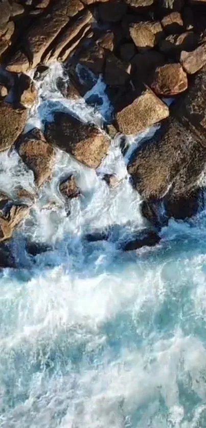 Aerial view of ocean waves crashing against rugged rocks on a sunny day.