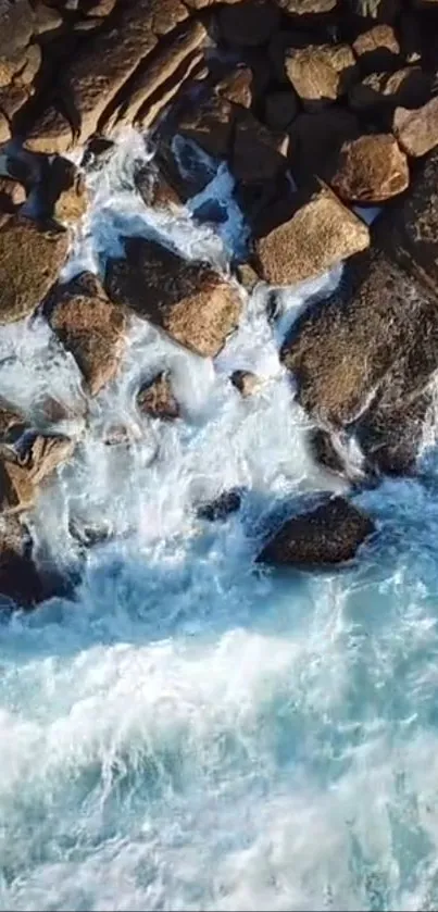 Aerial view of ocean waves hitting rocky shore with blue and earthy tones.