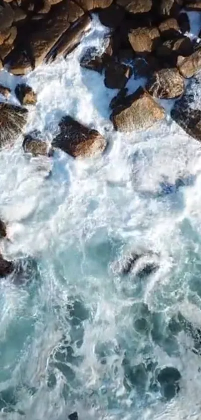 Aerial view of ocean waves crashing against rocky coastline with clear blue water.