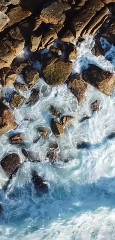 Aerial view of ocean waves crashing over rugged rocks.