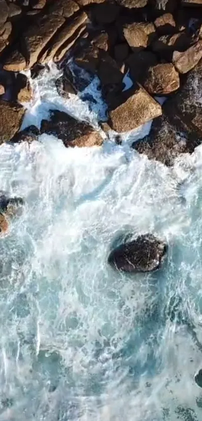 Aerial view of ocean waves crashing against rugged rocks.