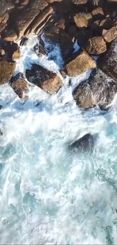 Aerial view of ocean waves crashing against rocky shoreline.