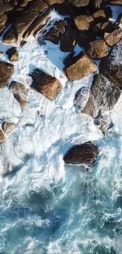 Aerial view of waves crashing over a rocky shore with vibrant blue water.