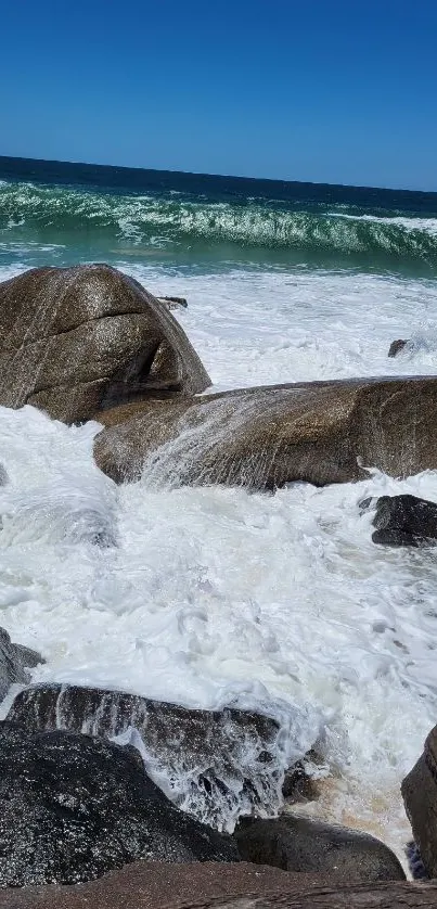 Crashing ocean waves on rocky shore with blue sky.