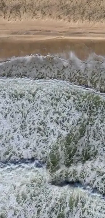 Aerial view of ocean waves crashing onto a sandy beach.