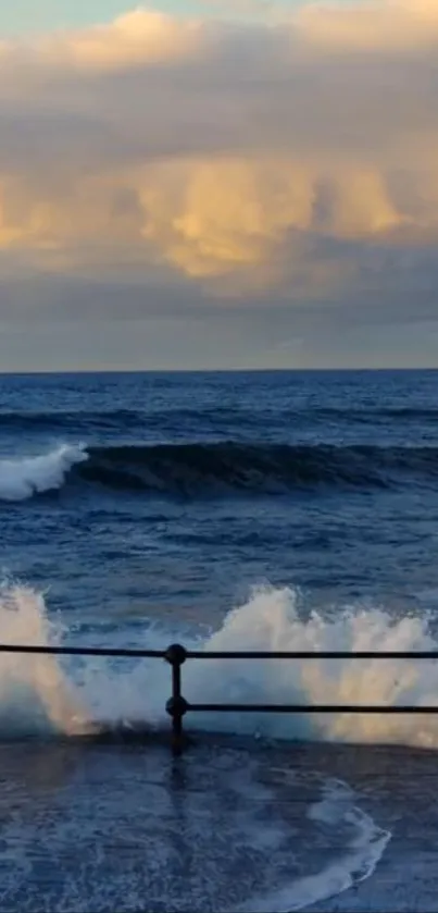 Ocean waves crash against a railing at sunset with a colorful sky.