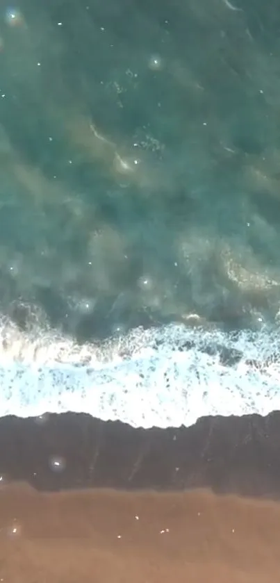 Aerial view of ocean waves meeting sandy beach with blue-green water.