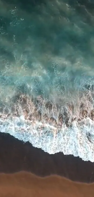 Aerial view of ocean waves crashing on the beach with teal water.