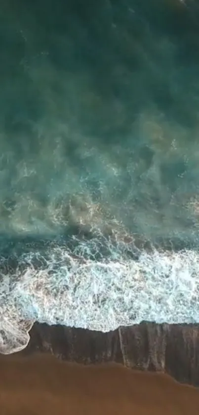 Aerial view of ocean waves gently washing onto a sandy beach.