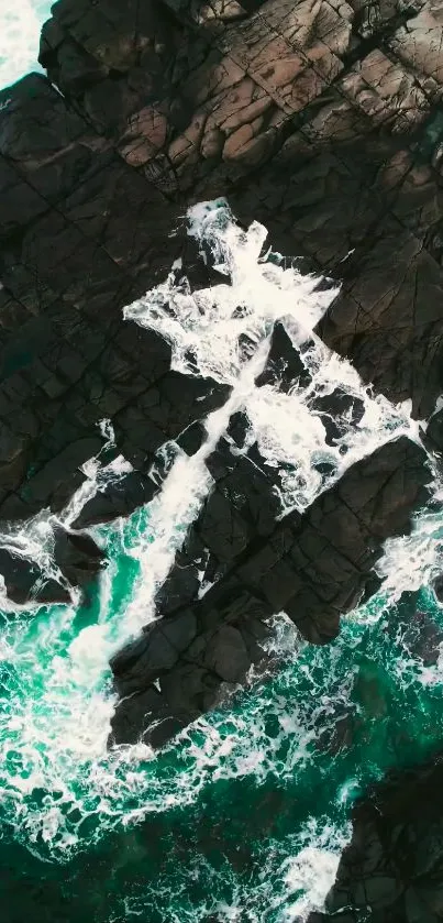 Aerial view of ocean waves crashing on rugged rocks, showcasing teal and dark hues.