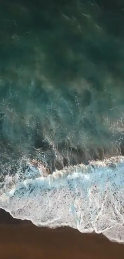 Aerial view of turquoise ocean waves crashing on a sandy beach.