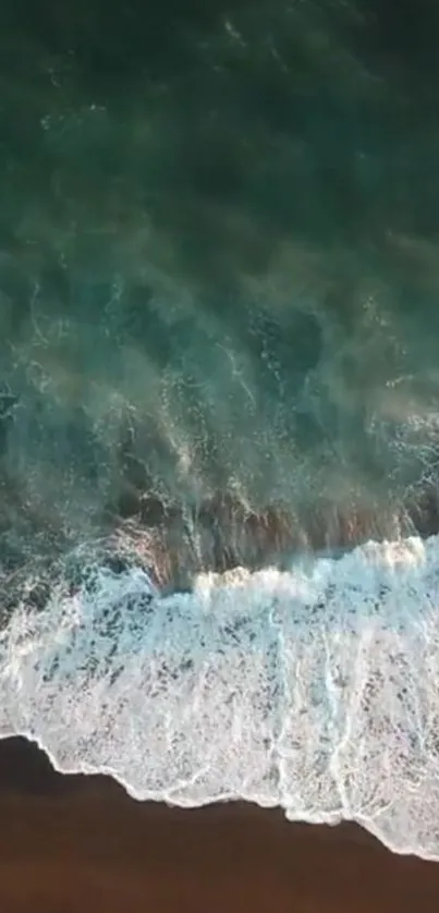 Aerial view of ocean waves crashing onto a beach, creating a tranquil mobile wallpaper scene.