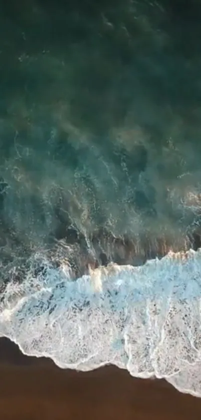 Aerial view of ocean waves crashing on a sandy beach creating a serene mobile wallpaper.