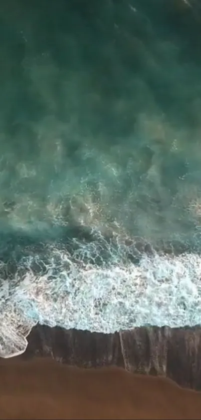 Aerial view of turquoise ocean waves hitting the sandy shore.