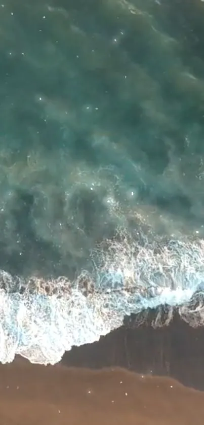 Aerial view of turquoise ocean waves meeting sandy beach.