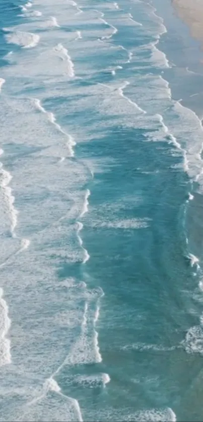 Aerial view of turquoise ocean waves gently hitting the sandy shore.