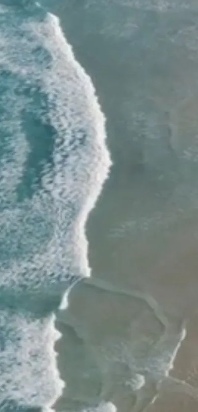 Aerial view of ocean waves on a sandy beach with a calming color palette.