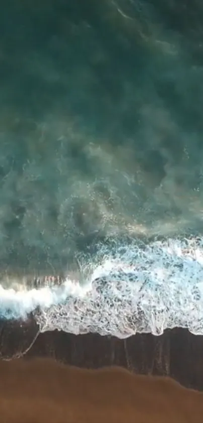 Aerial view of ocean waves gently hitting a dark sandy beach, creating a scenic vista.