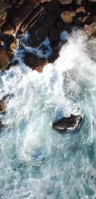 Aerial view of waves crashing on rocks with blue ocean water.