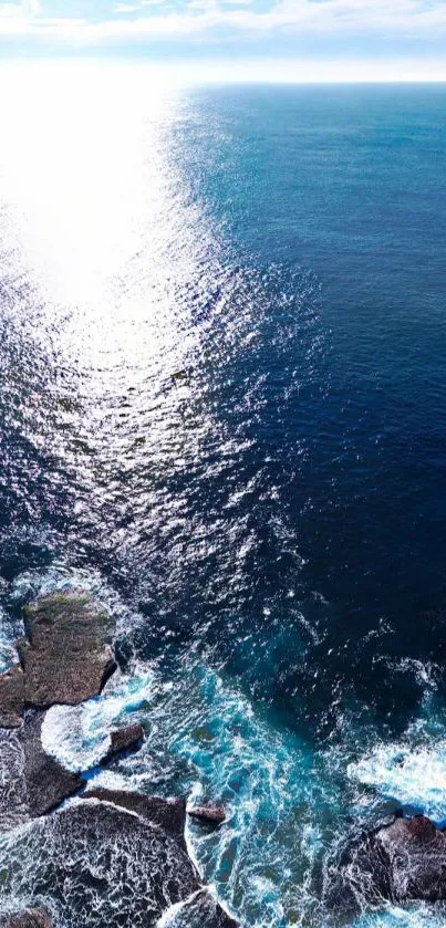 Aerial view of ocean waves with sunlight reflecting on the water surface.