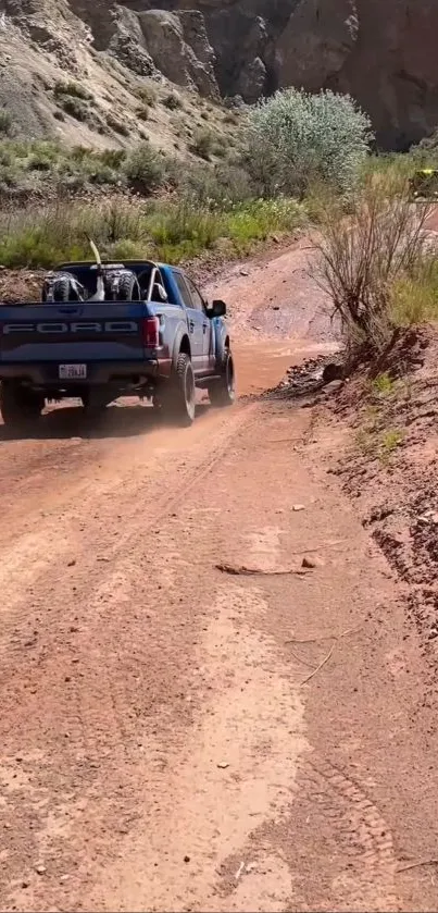 Blue truck driving on dusty off-road path with scenic background.