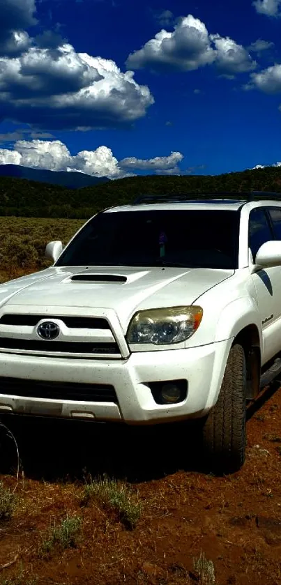 SUV parked in a mountainous landscape under a blue sky with clouds.