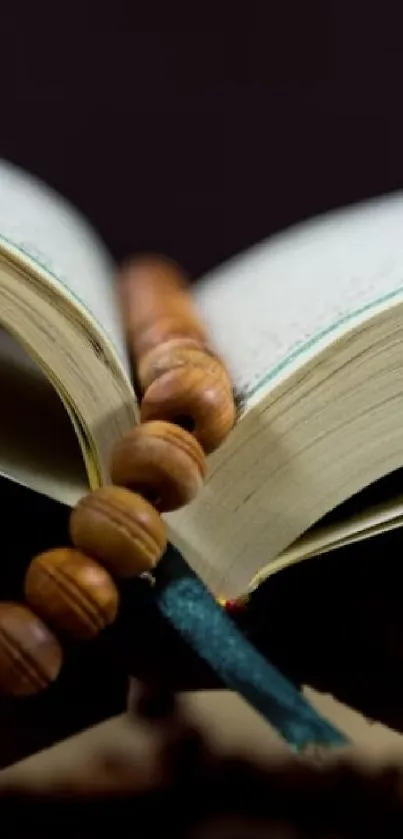 Open book with wooden prayer beads resting on pages.