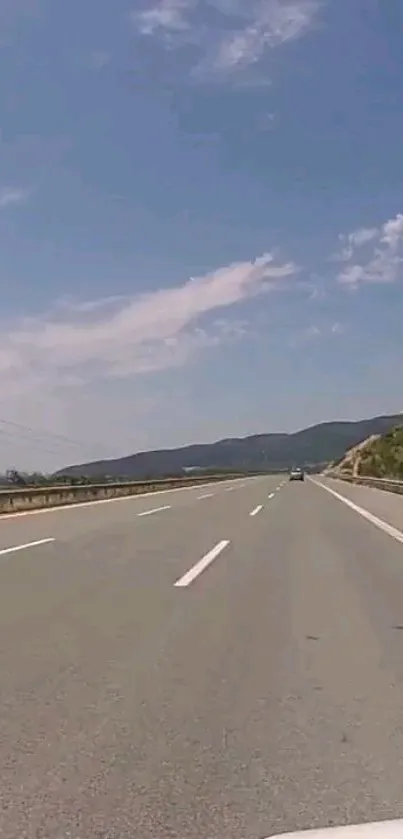 Highway under a clear blue sky with distant hills.