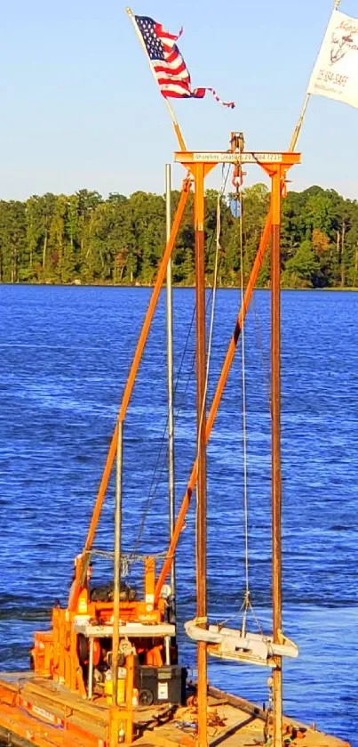 Orange barge floats on a blue lake with green trees in the background.